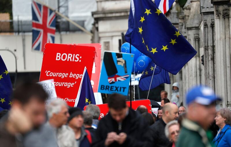 Pro and anti-Brexit supporters hold signs and flags while demonstrating outside the Parliament in London, Wednesday, Sept. 25, 2019. Lawmakers in Britain are returning to the House of Commons on Wednesday, following a Supreme Court ruling that Prime Minister Boris Johnson had acted illegally by suspending Parliament. (AP Photo/Frank Augstein)