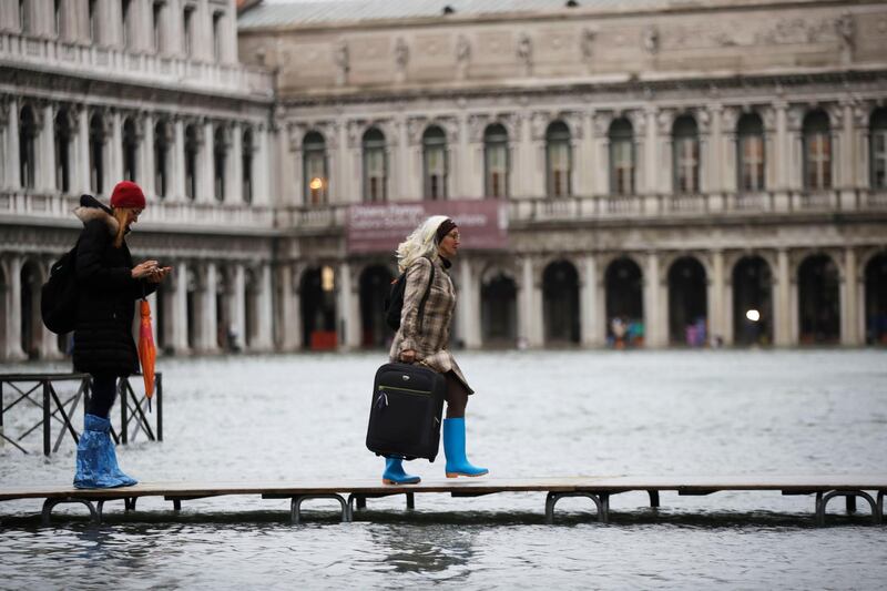 People use trestle bridges to walk in a flooded St. Mark's Square at Venice, Italy. AP Photo