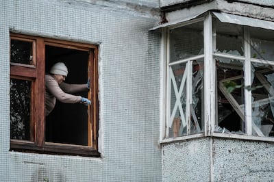 A woman removes a broken window at a building hit by a missile attack in Kharkiv. AFP