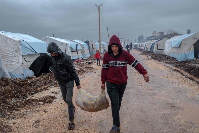 Men carry a sack of potatoes at a camp for people displaced by the February 6 earthquake, in Turkey's Adiyaman province. AFP