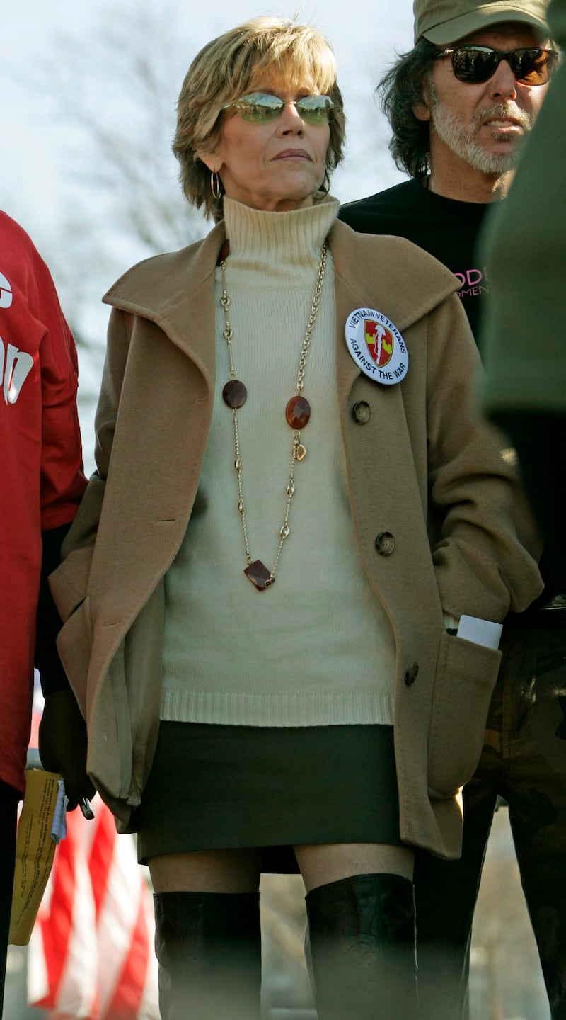 Jane Fonda, in a tan jumper and jacket, and a mini-skirt and knee-high boots, stands on stage during an anti-war protest rally and march on the National Mall in Washington, DC, on January 27, 2007