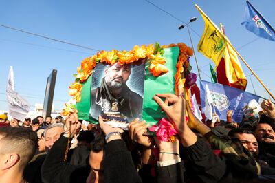 People carry a placard depicting commander from Kataib Hezbollah, Abu Bakir Al Saiedi, during his funeral in Baghdad on Thursday. Reuters