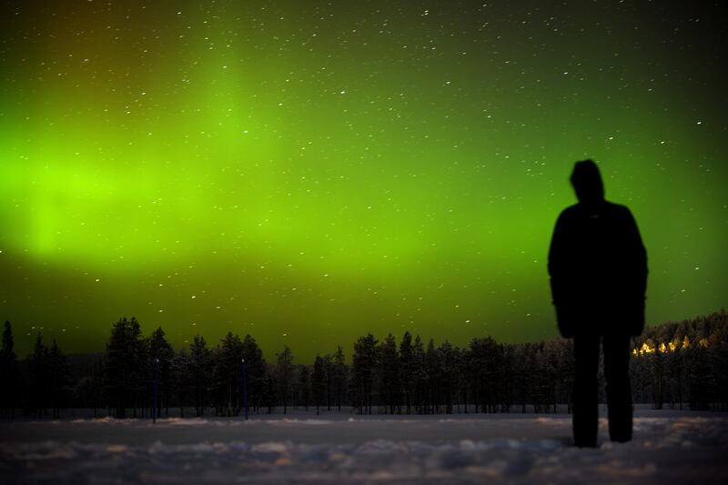 A person watches the Northern Lights (aurora borealis) illuminate the sky above the village of Akaslompolo in Lapland, Finland. EPA