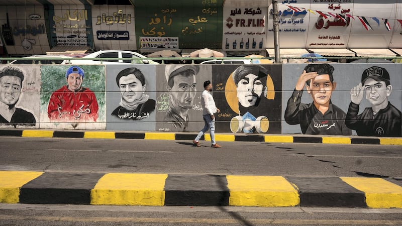 Mustafa Abd walking down Al Sadoon tunnel next to Tahrir square in the background portrait paintings of the martyrs. Haider Alhusseini for The National