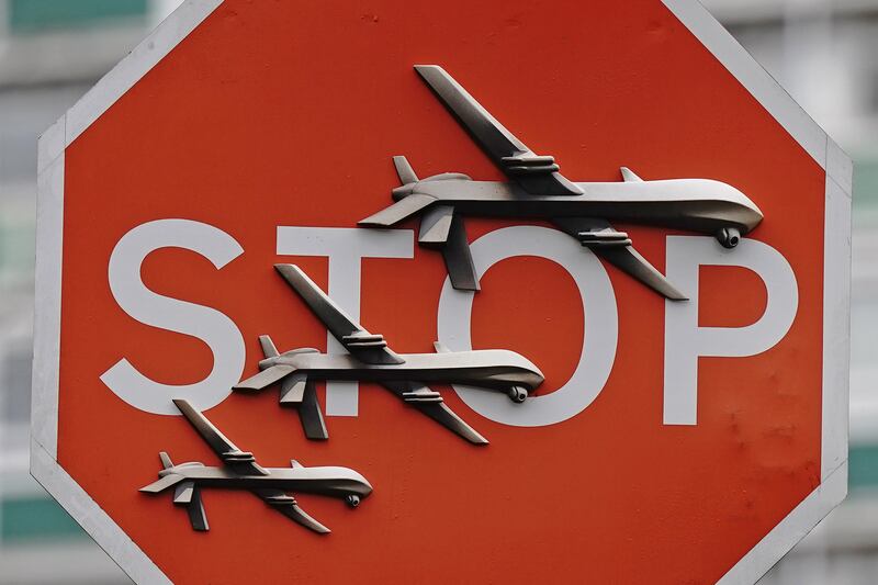 The artwork features three drones on a traffic Stop sign