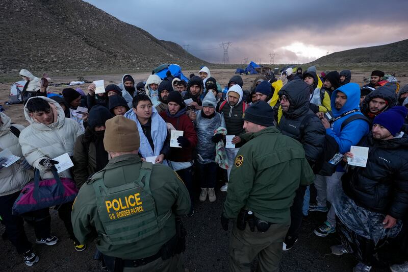 US Border Patrol agents speak with migrants, mainly from Colombia, China and Ecuador, sheltering in a makeshift campsite after crossing the border from Mexico near Jacumba, California. AP