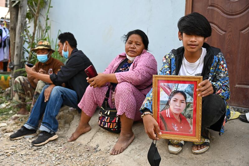 A youth holds a framed portrait of his mother who is missing following the Grand Diamond City hotel-casino fire in Poipet on December 30, 2022.  - Rescuers scoured the charred ruins of a Cambodian hotel and casino complex on December 30 as the death toll from a fire that forced people to jump from windows rose to 25.  (Photo by Tang Chhin Sothy  /  AFP)