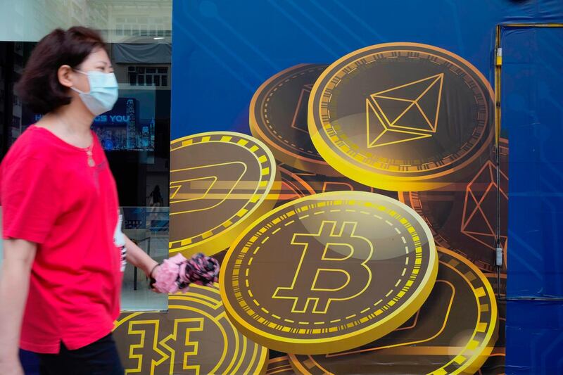 FILE - In this June 1, 2021, file photo, a woman walks past an advertisement for the Bitcoin cryptocurrency in Hong Kong. Chinaâ€™s biggest banks promised Monday, June 21, 2021, to refuse to help customers trade Bitcoin and other cryptocurrencies after the central bank said executives were told to step up enforcement of a government ban. (AP Photo/Vincent Yu, File)