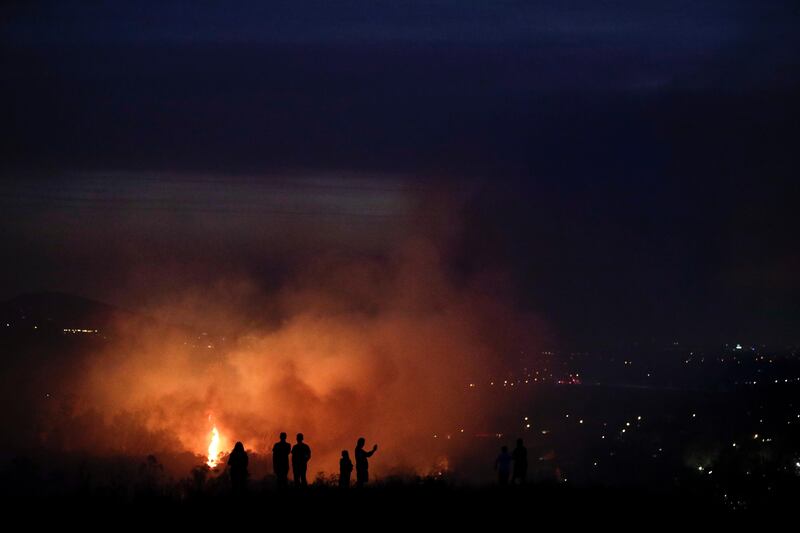 People watch as a wildfire burns along a hillside in Southern California. Jae C Hong / AP Photo