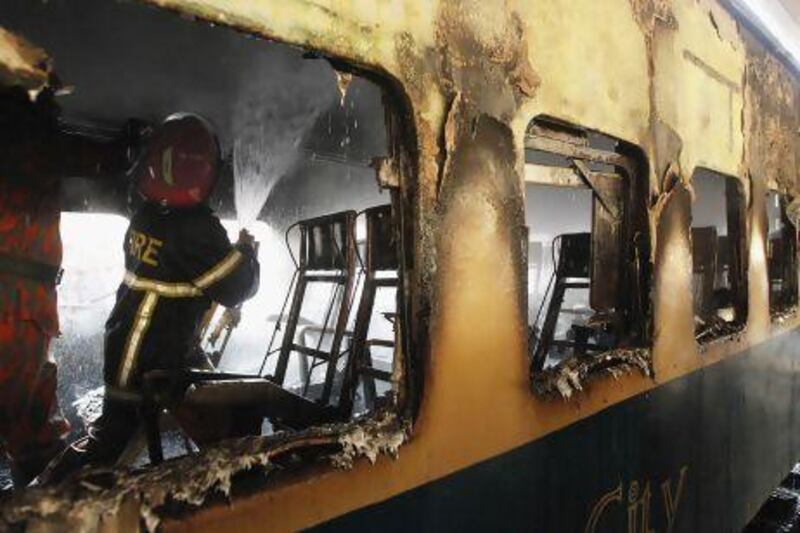 A fire fighter sprays water inside the burnt compartment of a train at Kamlapur Railway Station in Dhaka on Monday. Andrew Biraj / Reuters