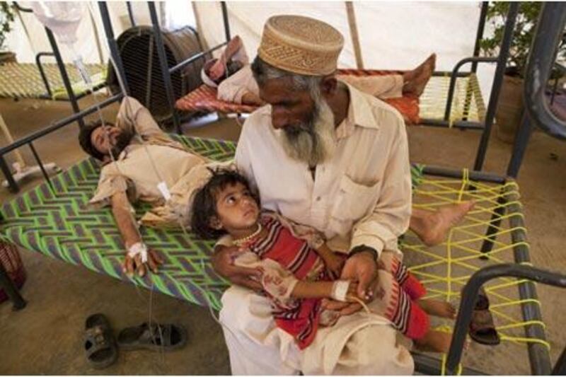 A Pakistani man holds his granddaughter, who is suffering from dehydration and a fever, in the Chota Lahore relief camp in Swabi.