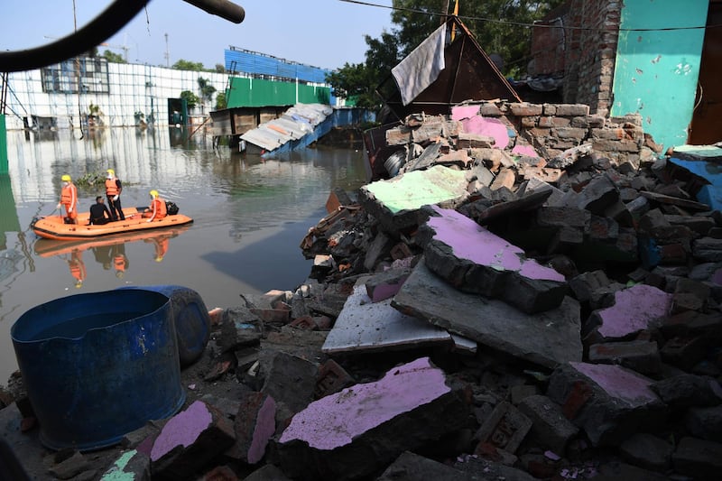 National Disaster Response Force personnel inspect on a dinghy the area where some shanty houses collapsed into a canal due to heavy rains in New Delhi, India. AFP