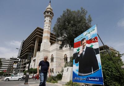 A Syria man walks past a giant portrait of President Bashar al-Assad at Marjeh square in the centre of capital Damascus on May 3, 2021. A Syrian former minister and a member of the Damascus-tolerated opposition will face Bashar al-Assad in this month's presidential election, the constitutional court said Monday. The Assad-appointed body approved only three out of 51 applications to stand in the May 26 ballot, among them the 55-year-old president himself,
 / AFP / LOUAI BESHARA
