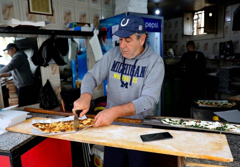 Abu Shadi cuts a freshly baked garnished flatbread before serving it to a customer. AFP