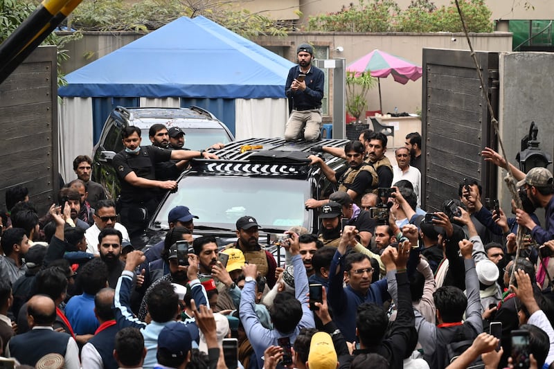 Supporters of former Pakistan's Prime Minister Imran Khan gather around his car as he leaves his residence in Lahore, on his way to appear in a court in Islamabad. AFP