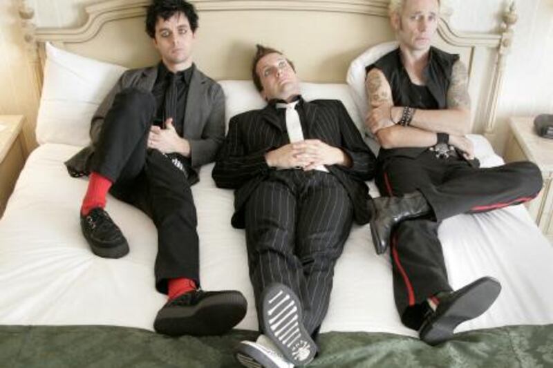 Members of Green Day,  Billie Joe Armstrong, left,, Tre Cool and Mike Dirnt, right,  pose for a photo between interviews in their Toronto hotel room, Thursday September 23, 2004. They have a new album out, "American Idiot," their first in four years.(AP Photo/CP,Adrian Wyld)