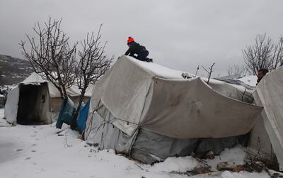 A Syrian boy clears snow covering a tent at a camp for internally displaced people, near the border with Turkey in Idlib. AFP