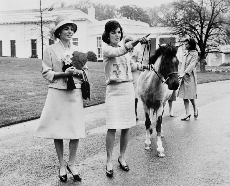 Jackie Kennedy leads her daughter Caroline's pony, Macaroni, while giving gives a tour of the White House grounds to Empress Farah Pahlavi of Iran in 1962. AP