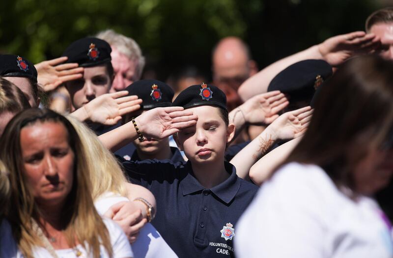 Cadets salute as they observe one minute silence as they gather to watch the service of commemoration. Leon Neal/Getty Images