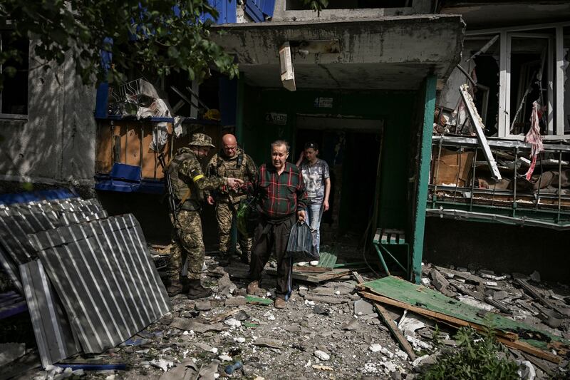 Ukrainian troops help an elderly man out of a damaged apartment building after an air strike in the city of Slovyansk in Donbas region. AFP