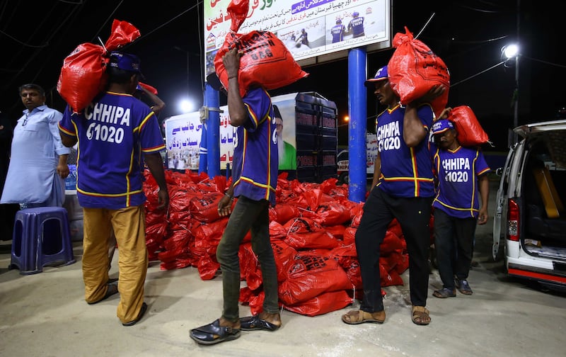 Volunteers from the Chhipa Welfare Association carry goods for distribution to flood victims following heavy rains, in Karachi. EPA