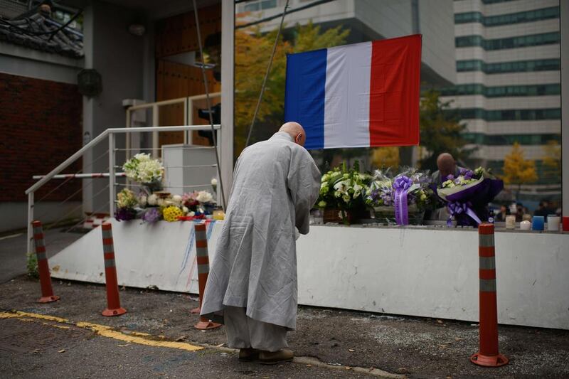 A Buddhist monk prays before tributes outside the French embassy in Seoul, South Korea, on November 16, 2015. At least 129 people were killed in the Paris attacks, with more than 350 injured, according to police. Ed Jones / Agence France-Presse