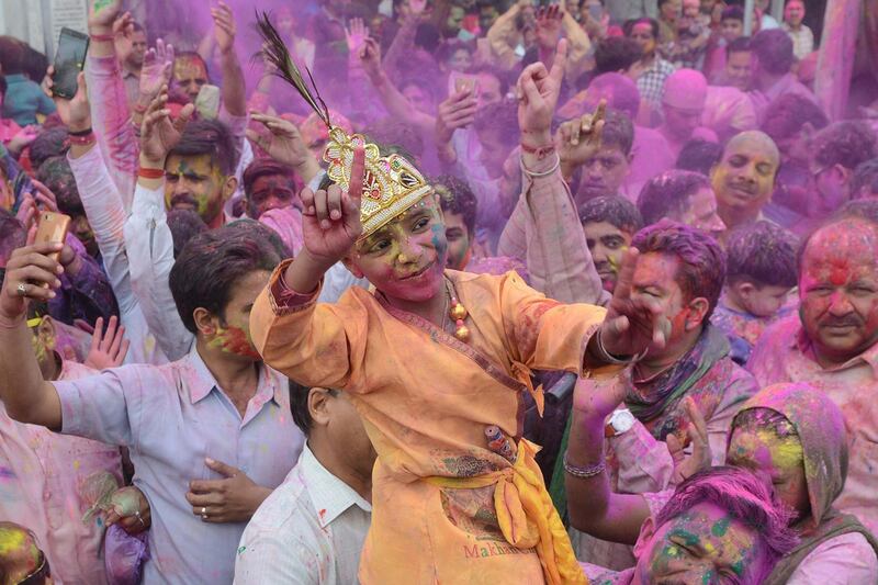 An Indian boy dressed as Lord Krishna dances along with devotees covered with coloured powder during Holi celebrations in Amritsar. Narinder Nanu / AFP Photo