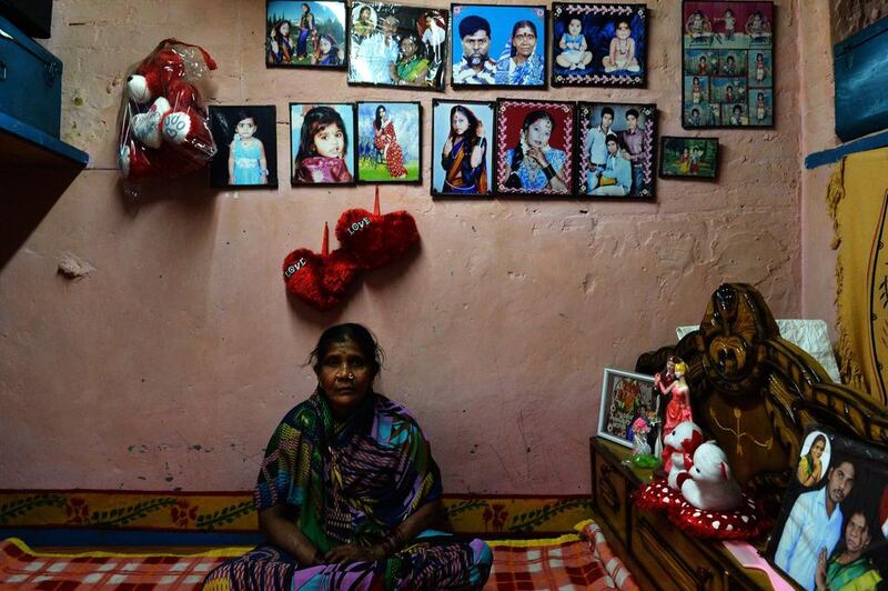 Patient Draupadi, 47, also cured of leprosy poses with pictures of her family.