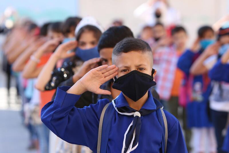 Schoolchildren salute the Syrian national anthem before entering their classes in Damascus, Syria.  EPA