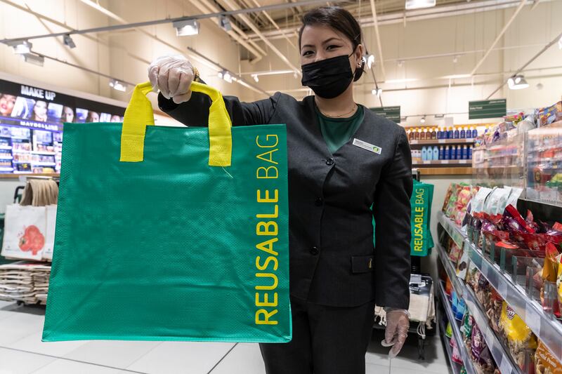 A Spinneys staff member holds up one of the supermarket's alternatives to single-use plastic bags. Antonie Robertson / The National
