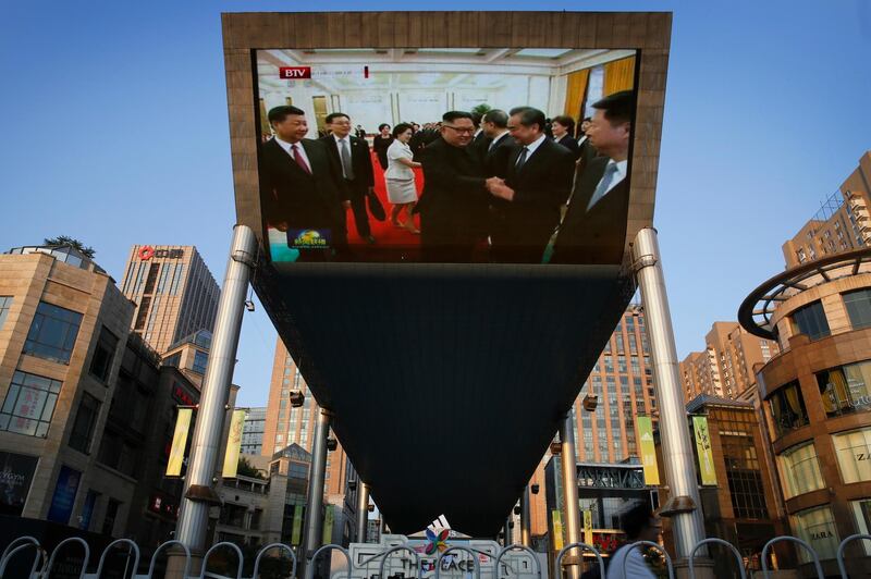 People cycle past a giant TV screen in Beijing broadcasting the meeting. Andy Wong / AP Phoyo