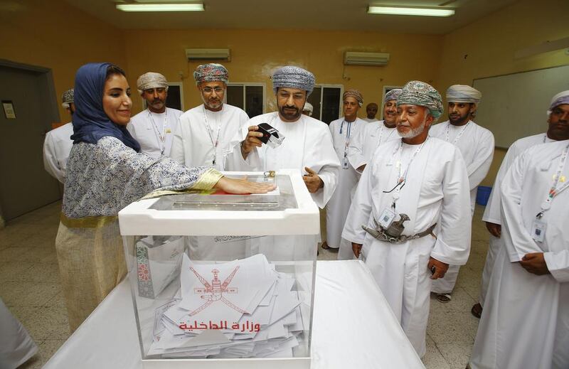 Omani interior minister Hamoud bin Faisal Al Busaidi (C) seals a ballot box at a polling station in Muscat for shura council elections on October 25. AFP Photo





