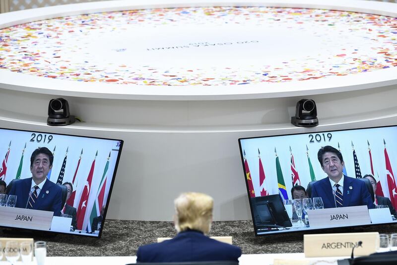 Mr Trump sits before screens showing Mr Abe during a meeting. AFP