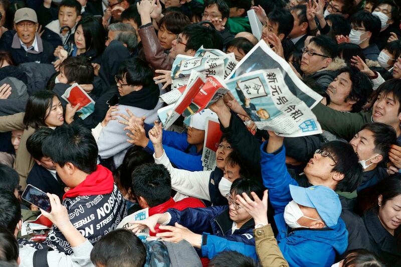 People reach out for copies of newspaper reporting the name of new era "Reiwa" in Osaka. AP