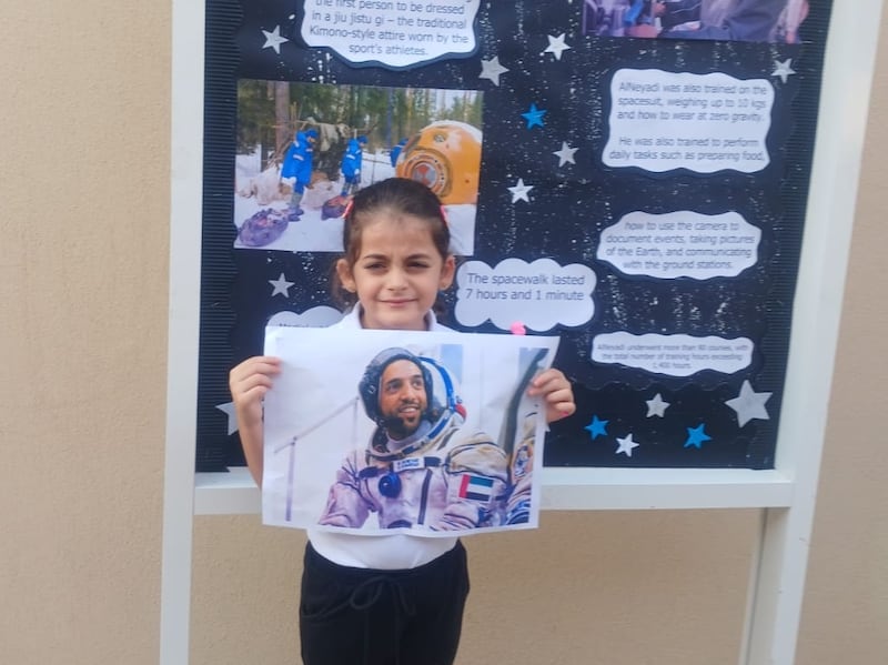 A pupil at Al Sanawbar School holds a picture of Dr Al Neyadi in celebration of his space mission.  Al Sanawbar School
