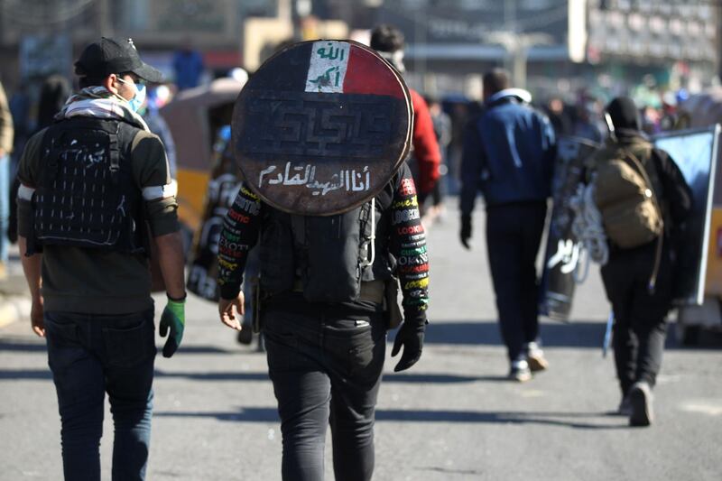 An Iraqi protester walks away while carrying on his back a makeshift shield with the inscription "I am the next martyr", during an anti-government demonstration in Al-Khilani square in the capital Baghdad.  AFP