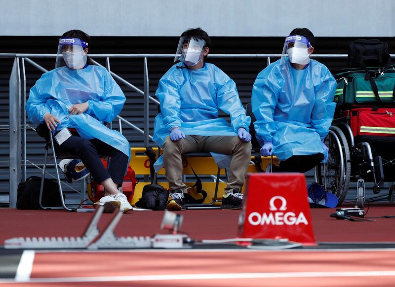 Medical officers wearing protective suits are seen at the morning session of the athletics test event. Reuters