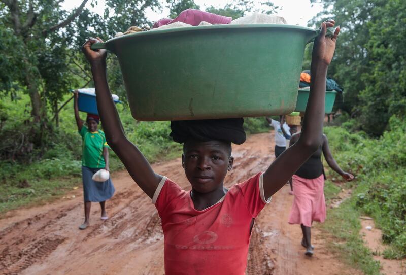 A young man poses for a portrait while carrying belongings in a tub on his head in Chipinge, Zimbabwe. Getty Images
