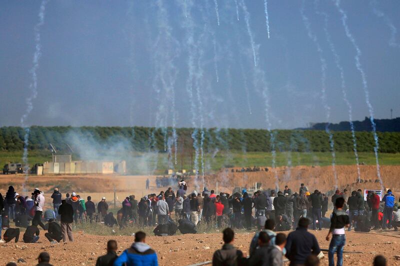 Teargas canisters fired by Israeli troops fall down on Palestinians during a demonstration near the Gaza Strip border with Israel, in eastern Gaza City, Friday, March 30, 2018. Thousands of Palestinians marched to the border in the largest such demonstration in recent memory, and 15 were killed by Israeli fire on the first day of what Hamas organizers said will be six weeks of daily protests against a stifling border blockade. (AP Photo/Khalil Hamra)