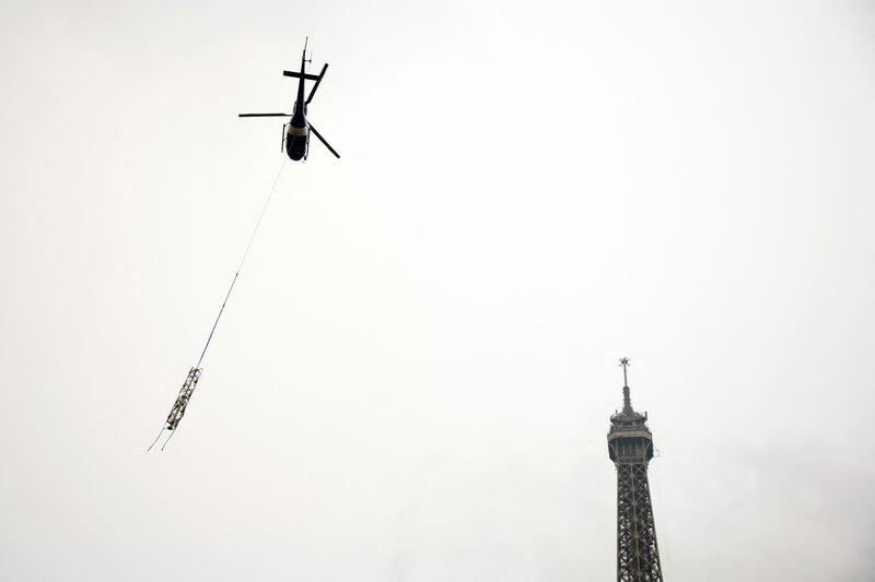 A helicopter flies next to the Eiffel Tower to place a new telecoms transmission antenna on its top, in Paris, France. Reuters