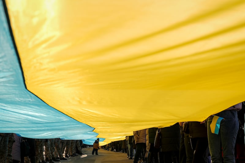 A child walks under a large Ukrainian flag carried by people marking Wednesday's 'day of unity' in Sievierodonetsk, eastern Ukraine. AP