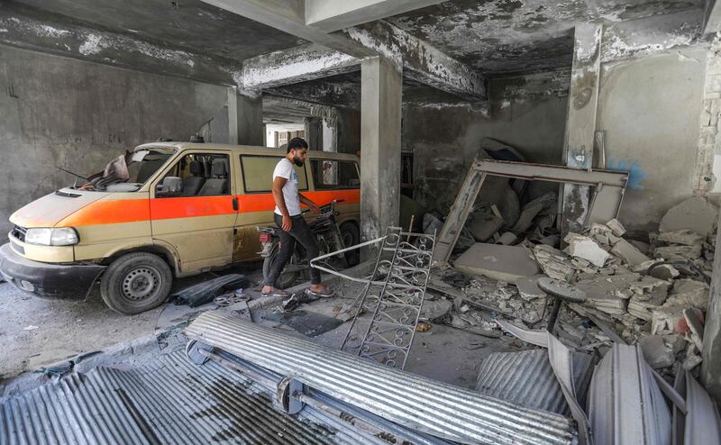 A man walks past a damaged mini-van that was used as a make-shift ambulance amidst debris in the garage of a hospital damaged after a reported air strike in Jisr al-Shughur in the northeastern Syrian Idlib province on July 10, 2019. Regime air strikes on July 10 killed several civilians including children in the town of Jisr al-Shughur, said the Britain-based Syrian Observatory for Human Rights, which relies on a network of sources inside the country. The raids are the latest in an uptick in government and Russian bombardment since late April on the jihadist-administered region of Idlib despite a months-old truce deal. / AFP / Omar HAJ KADOUR
