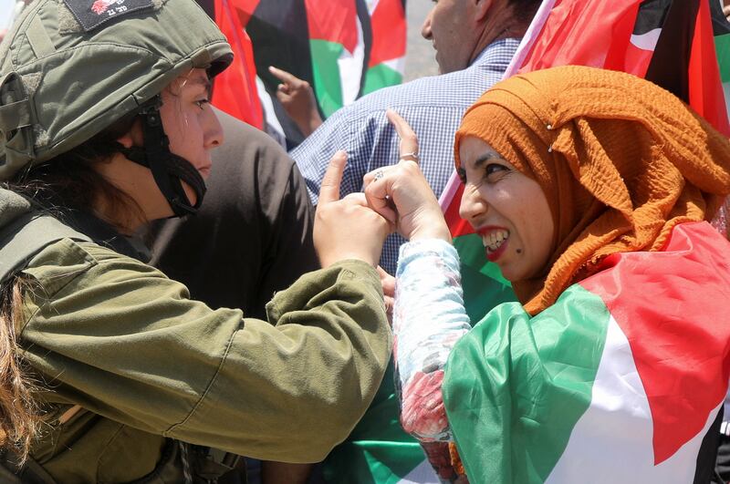An Israeli soldier argues with a demonstrator wrapped in a Palestinian flag during a protest against Israeli settlements in Jordan Valley, in the Israeli-occupied West Bank. Reuters