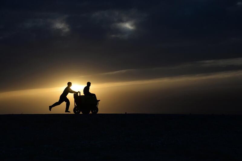 An Afghan youth pushes a friend on a ice-cream cart, as the sun sets on the outskirts of Mazar-I- Sharif. Farshad Usyan / AFP