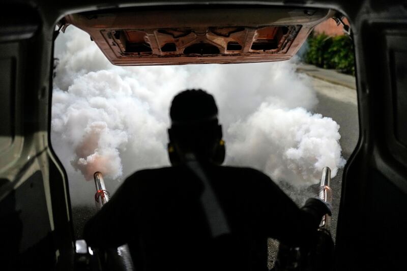 A worker fumigates a neighbourhood against dengue-promoting mosquitoes, in Caracas, Venezuela. AP