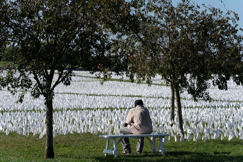 A visitor sits on a bench near the memorial. AP