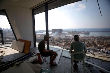 Two men gaze at the devastated Beirut port from a damaged building in the nearby neighbourhood of Mar Mikaehl. AFP