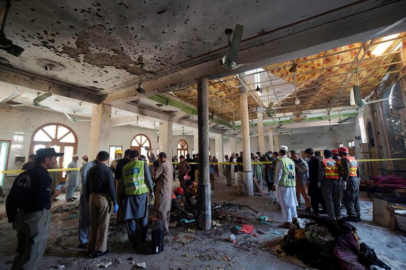 Security officials examine the site of a blast at a religious school in Peshawar.  AFP