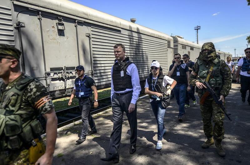 Monitors from the Organisation for Security and Cooperation in Europe (OSCE) and members of a forensic team inspect a refrigerator wagon containing the remains of victims from the downed Malaysia Airlines Flight MH17, at a railway station in the eastern Ukrainian town of Torez on July 21, 2014. Bulent Kilic/AFP Photo