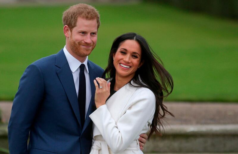 (FILES) In this file photo Britain's Prince Harry stands with his fiancée US actress Meghan Markle as she shows off her engagement ring whilst they pose for a photograph in the Sunken Garden at Kensington Palace in west London on November 27, 2017, following the announcement of their engagement. Queen Elizabeth II and other senior British royals were gathering for a meeting Monday with Prince Harry in an attempt to solve the crisis triggered by his bombshell announcement that he and wife Meghan were stepping back from the royal frontline. Harry's father Prince Charles and brother Prince William, with whom he has strained relations, will join the monarch at her private Sandringham estate in eastern England, according to British media. / AFP / Daniel LEAL-OLIVAS
